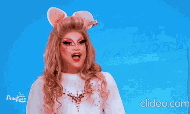 a drag queen is standing next to a piece of paper that says " camaron de la zola "