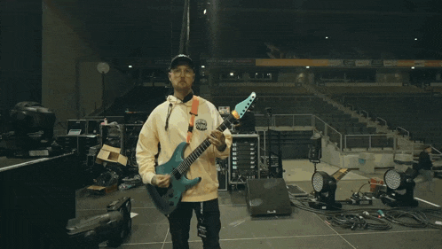 a man holding a guitar in front of an empty stadium with a sign that says ' stadium ' on it