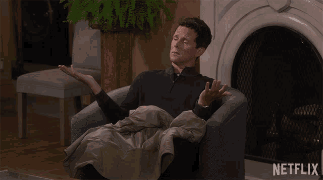 a man is sitting in a chair in front of a fireplace with a netflix logo on the bottom right