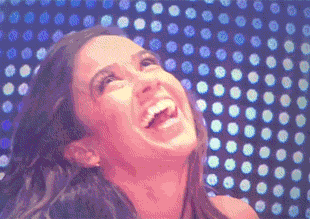 a woman is laughing in front of a wall with polka dots on it .