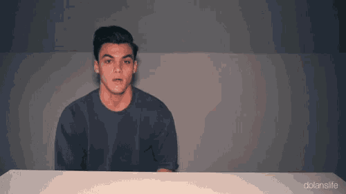 a man in a blue shirt is sitting at a table with his mouth open .