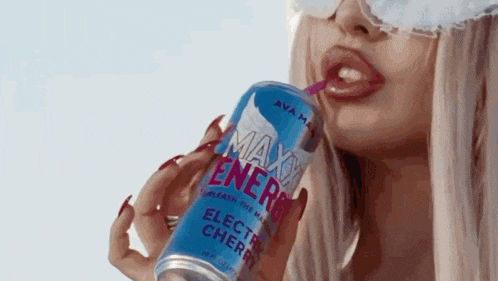 a woman is drinking from a can of max energy