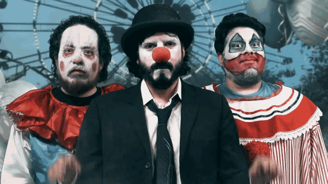 a group of clowns are posing for a photo in front of a ferris wheel