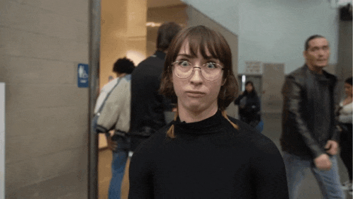 a woman making a funny face in front of a handicap accessible bathroom