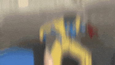 a blurry picture of a person wearing a yellow and blue shirt