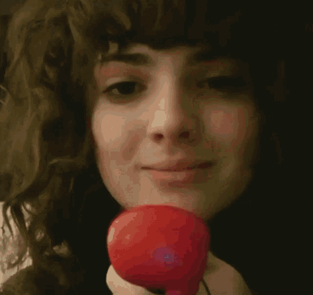a woman with curly hair is smiling while holding a black object