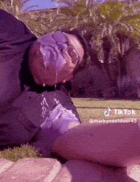 a man with purple paint on his face is laying on a brick sidewalk