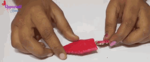 a close up of a person 's hands holding a piece of red fabric ..