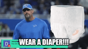 a man wearing a blue shirt stands next to a diaper that says wear a diaper !!!