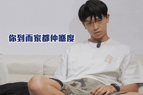 a man wearing a white t-shirt with a fox on it sits on a couch