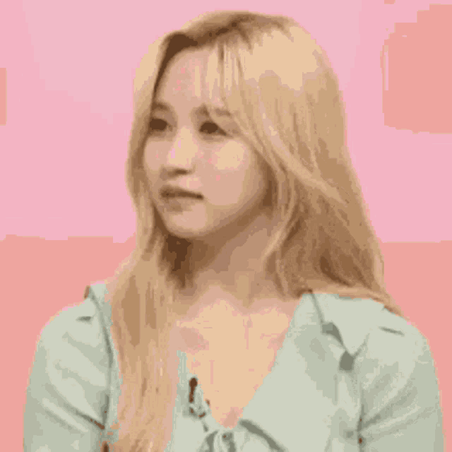 a woman with blonde hair is wearing a blue shirt and looking at the camera .