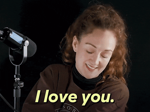 a woman in front of a microphone says i love you in yellow letters