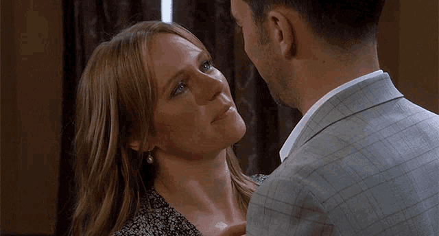 a man in a suit and a woman in a floral dress are looking at each other