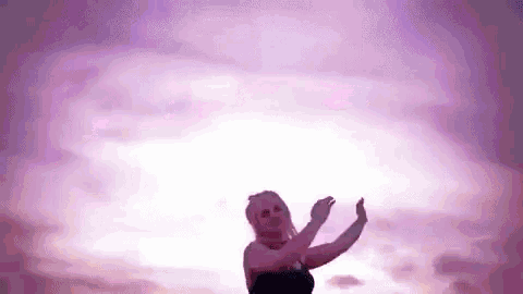a woman is standing in front of a purple sky with a lightning bolt .