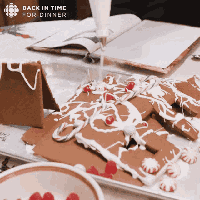 a gingerbread house is being decorated with white frosting and candy canes and the words back in time for dinner above it