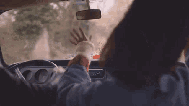 a man and a woman are driving a car down a road with their hands up in the air .