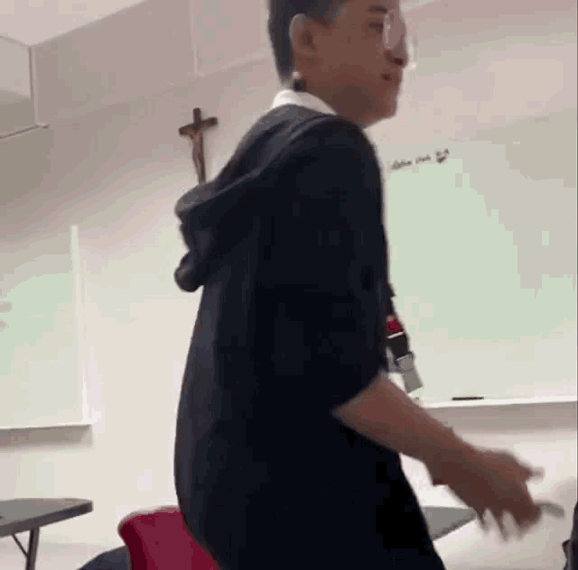 a young man is standing in a classroom in front of a whiteboard .