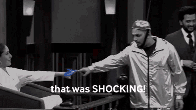 a black and white photo of a man pointing at a woman with the words that was shocking behind him