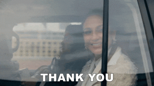 a woman is sitting in the back seat of a car with the words `` thank you '' written on the window .