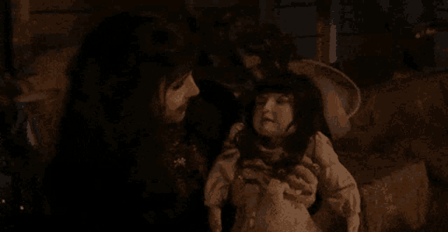 a woman with vampire teeth is holding a doll in her hands