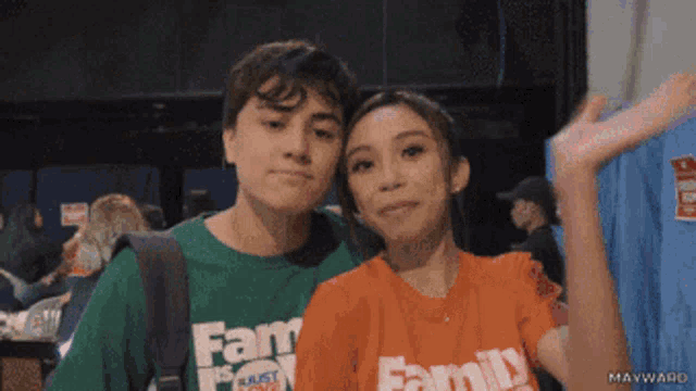 a boy and a girl are posing for a picture and the girl is wearing an orange shirt with the word family on it