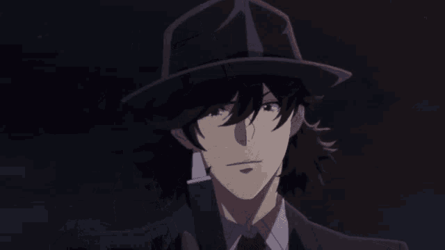a man in a suit and hat is talking on a cell phone and says " what 's up "