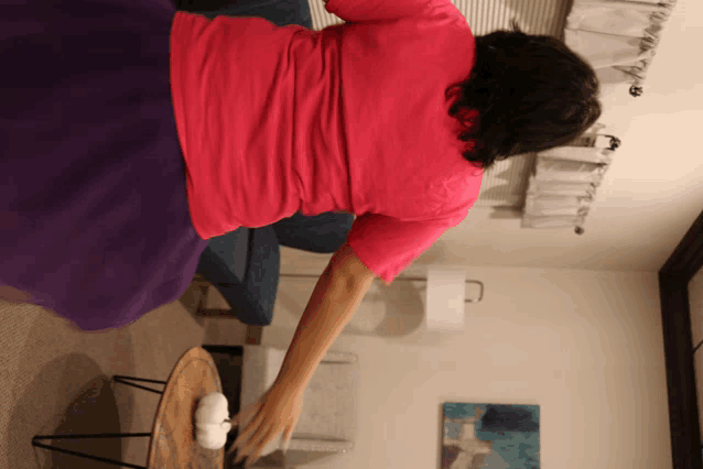 a woman in a pink shirt is sitting on a purple couch