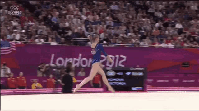 a gymnast performs a trick in front of a london 2012 banner