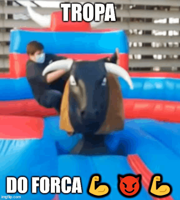a man wearing a mask is riding a bull on a bouncy castle ..