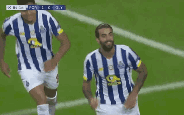 two soccer players in blue and white striped jerseys are running on a field .