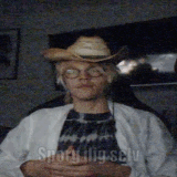 a man wearing a cowboy hat and glasses is sitting in a dark room ..