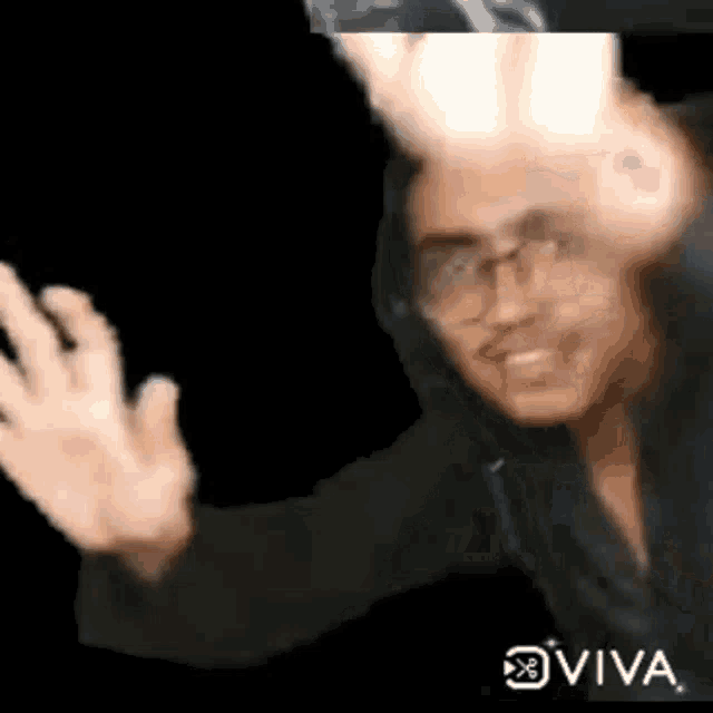 a man wearing glasses and a hoodie is making a funny face with his hands in the air .
