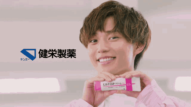a man in a pink shirt is holding a pink and white item with chinese writing