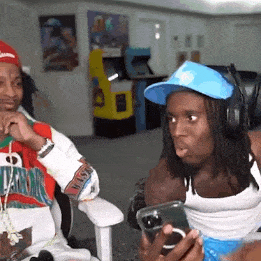 a man wearing a blue hat and headphones is sitting next to another man .