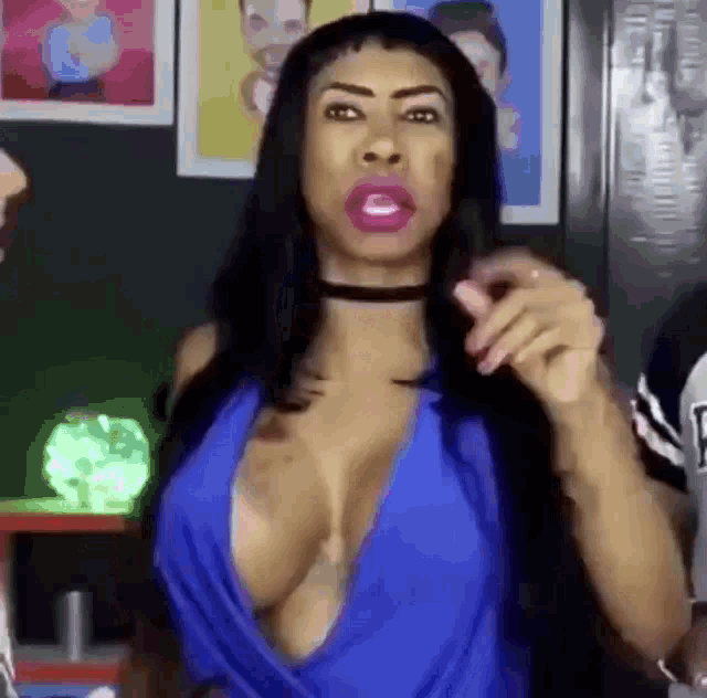 a woman with a choker around her neck is wearing a very plunging blue top .