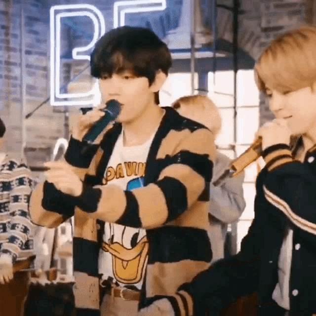 a man wearing a donald duck shirt is singing into a microphone