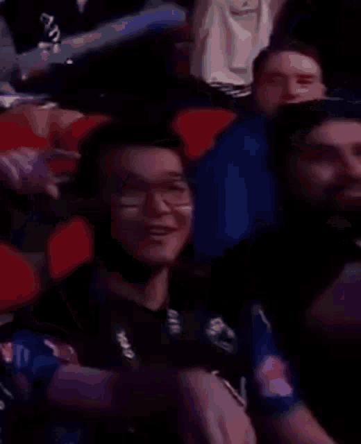 a crowd of people are sitting in a stadium watching a game and one of them is wearing a hat .