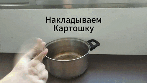 a person is stirring a pot with a wooden spoon in front of a sign that says nakladivaem kartoshka