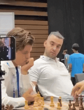 two men are playing a game of chess and one of them is wearing a shirt that says ' adidas '