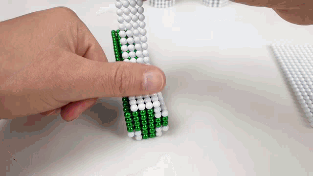 a person 's hand is holding a green and white ball