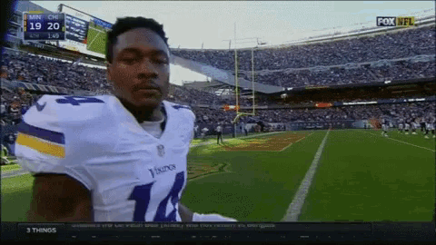 a football player in a vikings uniform stands in front of a crowd