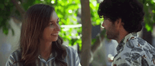 a man and a woman are looking into each other 's eyes and smiling .
