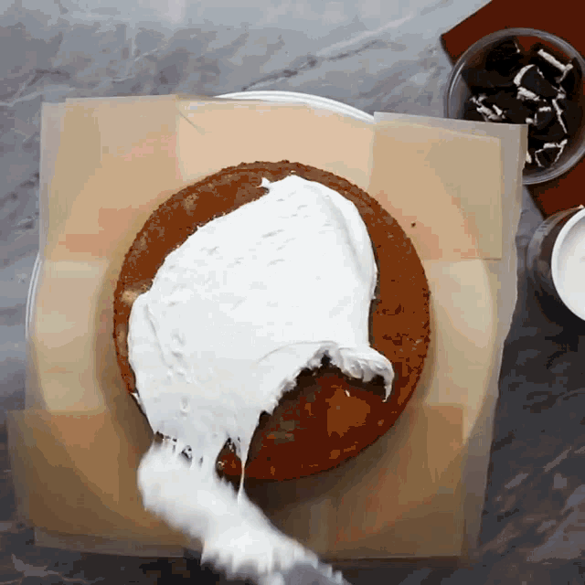 someone is spreading frosting on a cake on a table