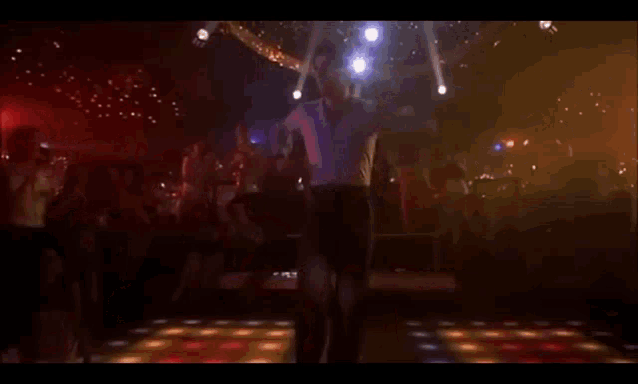 a man is dancing on a dance floor in front of a crowd in a nightclub .