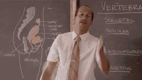 a man in a suit and tie is standing in front of a chalkboard .