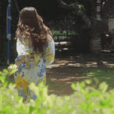 a woman in a floral robe is walking in a garden