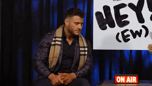 a man is sitting in front of a sign that says hey crew