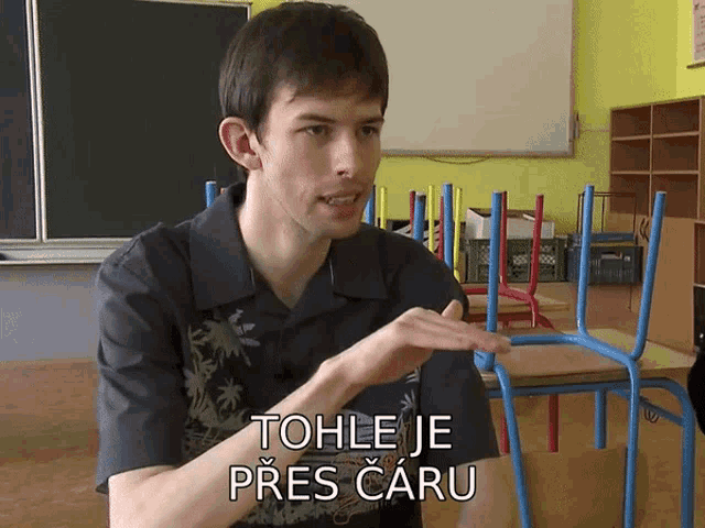 a man sitting in a classroom with the words tohle je pres caru on the bottom of his shirt