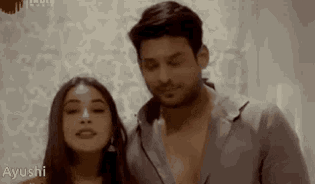 a man and a woman are standing next to each other with ayushi written on the bottom right