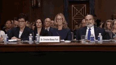 a group of people sitting at a table with a sign that says dr. christine blaney ford